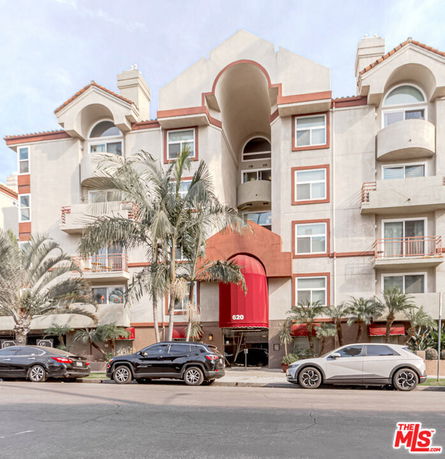 Front view of a multi-story apartment building with balconies and decorative arch.