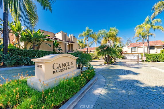 Front view of building with a sign for Cancun Racquet Club and palm trees.