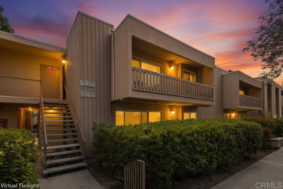 Front view of a two-story building with balconies and exterior lighting at twilight.