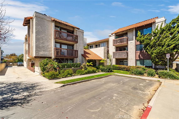 Front view of a multi-story apartment building with balconies and tiled roofs.