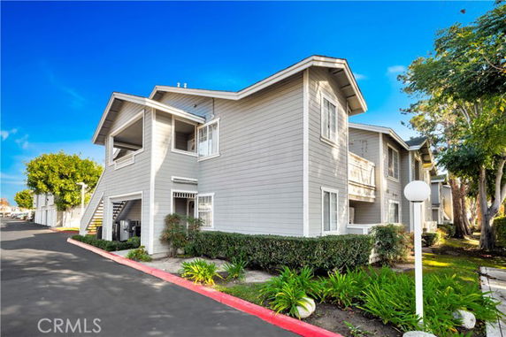 Front view of a two-story residential building with white siding and balconies.
