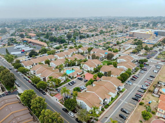 Aerial panoramic view of a residential neighborhood with multiple houses and parking areas.