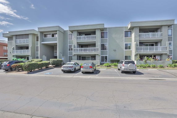 Front view of a three-story apartment building with balconies.