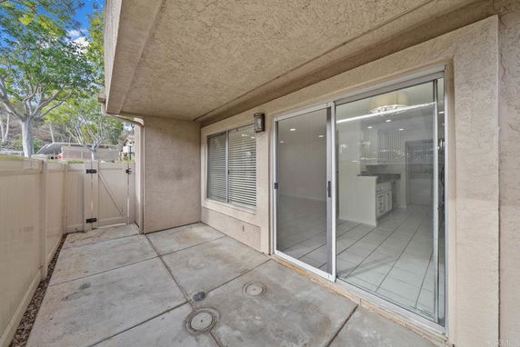 View of a house exterior with sliding glass doors opening to a small patio area.