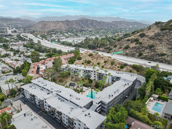 Aerial view of residential buildings surrounded by hills and highways.