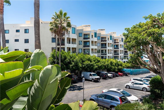 View of a multi-story apartment building with a parking area in front.