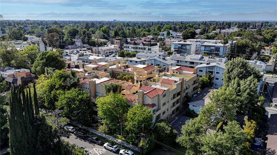 Aerial view of a complex of multi-story buildings with red-tiled roofs surrounded by trees and other buildings.