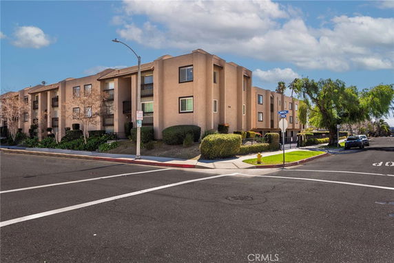 Front view of a multi-story apartment building at a street intersection.