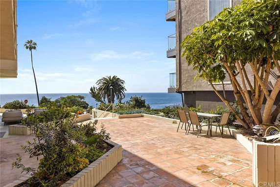 Outdoor terrace with ocean view and adjacent building.