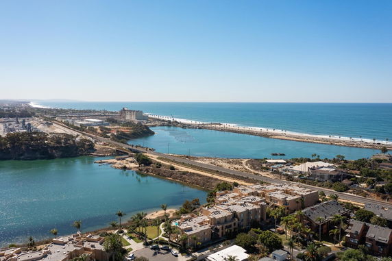 Panoramic view of a coastal area with buildings, a waterway, and the ocean in the background.