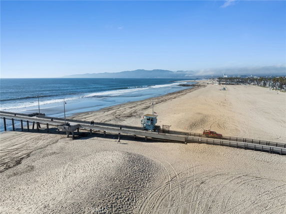 Wide view of a beach with a pier extending into the ocean.
