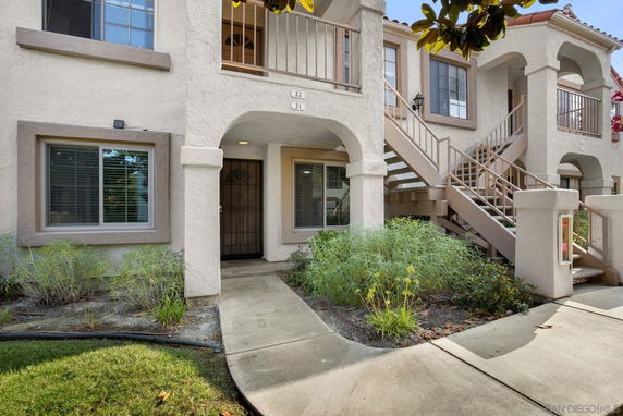 Front view of a two-story residential building with stairs leading to upper units.