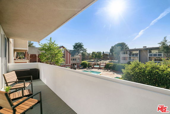 Outdoor balcony with chairs overlooking a courtyard and nearby residential buildings.