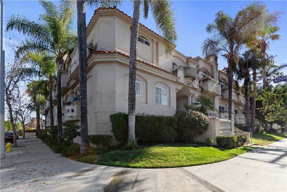 Front view of a multi-story building with balconies and palm trees.