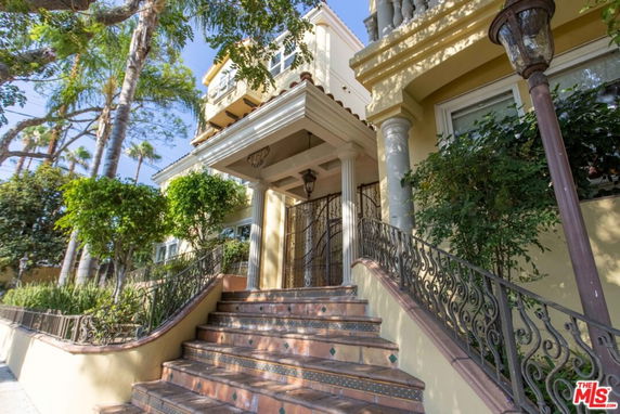 Front view of a multi-story house with ornate railings and a covered entrance.