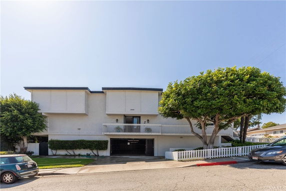 Front view of a multi-story building with a balcony and garage entrance.