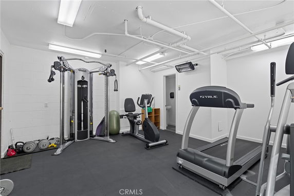 Room with gym equipment including treadmill and weight machines.