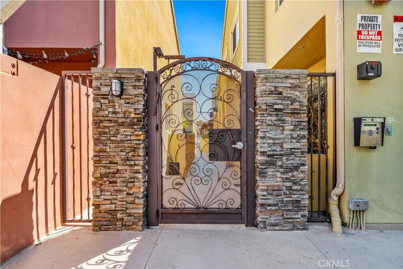 Front view of a house entrance with a decorative iron gate and stone pillars.