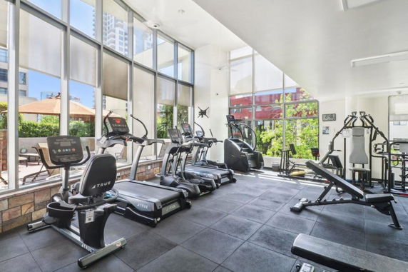 Gym area with various exercise equipment and large windows.