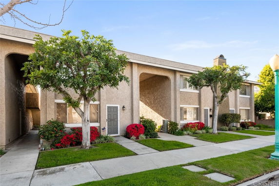 Front view of a two-story townhouse with arches and a well-maintained garden.