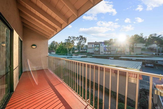 View from a balcony overlooking residential buildings and covered parking.