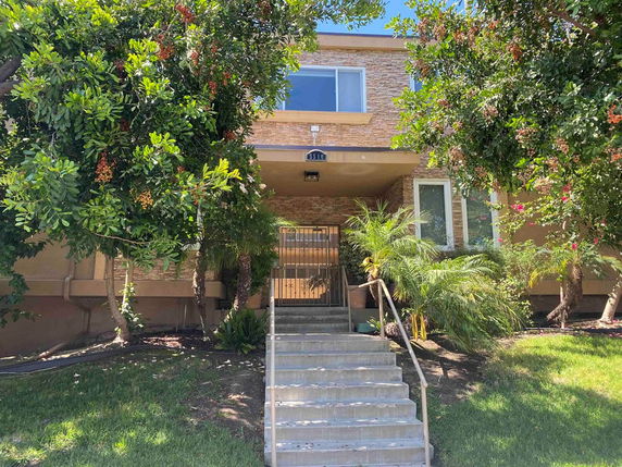 Front view of a two-story house with a staircase leading to the entrance.
