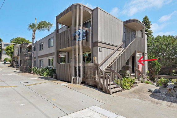 Front view of a two-story building with exterior stairs and vertical slats.