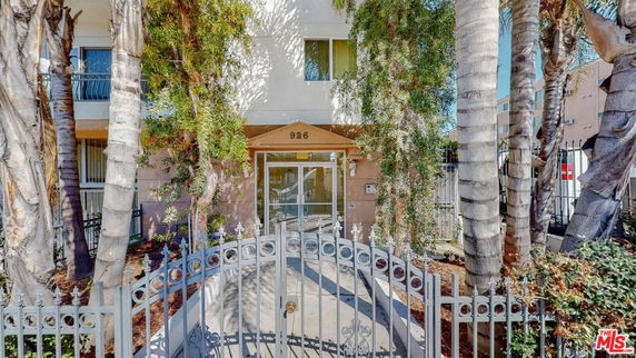 Front view of a building with a gated entrance and surrounding trees.