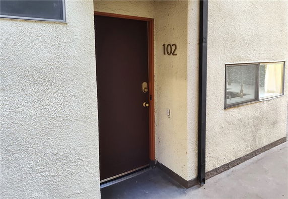 Front view of an entrance door to a building with the number 102 displayed.