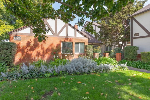 Front view of a single-story house with red brick exterior and triangular roof accents.