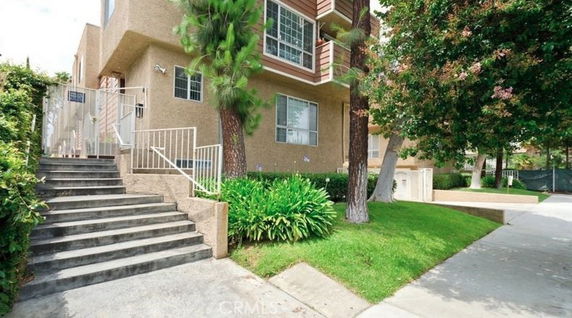 Front view of a multi-story residential building with stairs leading up to the entrance.