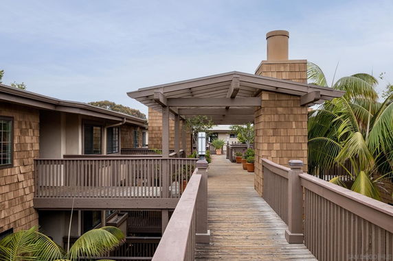 Rooftop walkway with a wooden railing and overhead covering.