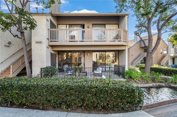 Front view of a two-story residential building with a balcony and outdoor seating area.