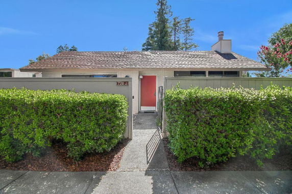 Front view of a single-story house with a red door and a shingled roof.