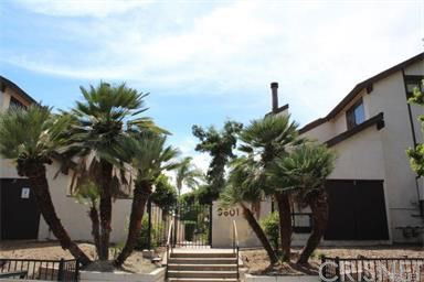 Front view of a multi-story building with palm trees and stairway.