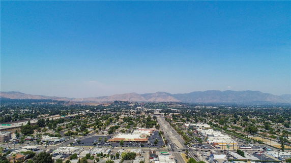 Panoramic view of a city with streets and buildings, mountains in the background.