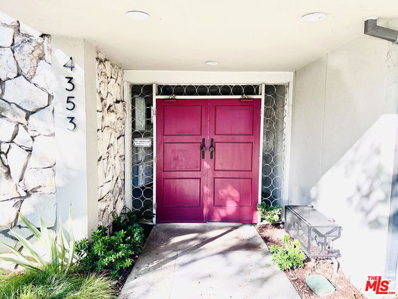 Front view of a building with a bright pink double door entrance and stone wall accents.
