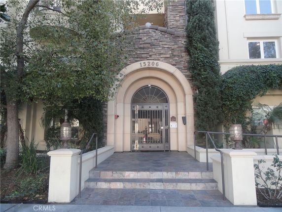 Front view of a building entrance with an arched doorway and stone facade.
