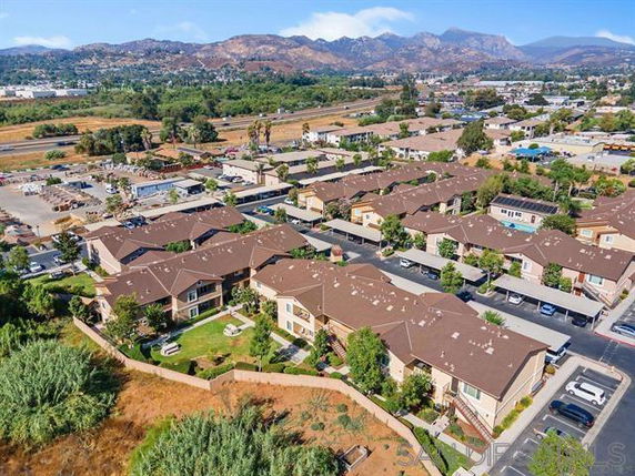 Aerial view of residential buildings in a neighborhood, with mountains in the background.