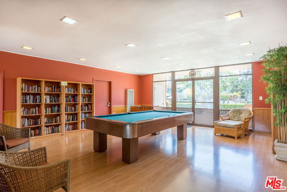 Room with a billiards table and bookshelves in a recreational area.