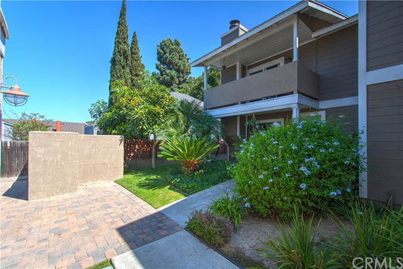View of a multi-story house with a balcony and landscaping.
