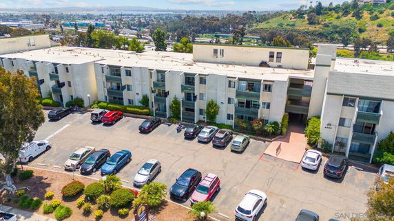 Front view of a multi-story apartment building with a parking area.