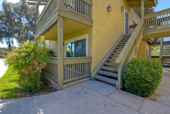 Front view of a two-story apartment building with exterior stairs and wooden railing.