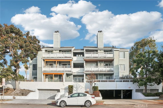 Front view of a multi-story apartment building with balconies and garages.