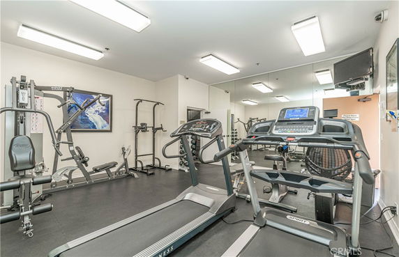 Indoor gym area with various exercise equipment including treadmills and weights.