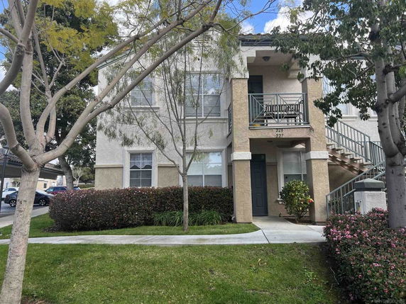 Front view of a two-story house with an external staircase and small balcony.