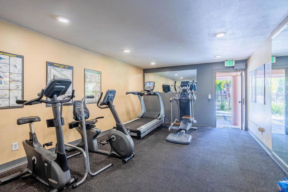 Indoor gym area with exercise machines and wall posters.
