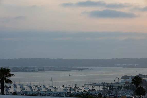 Panoramic view of a harbor with boats and distant buildings on a cloudy day.