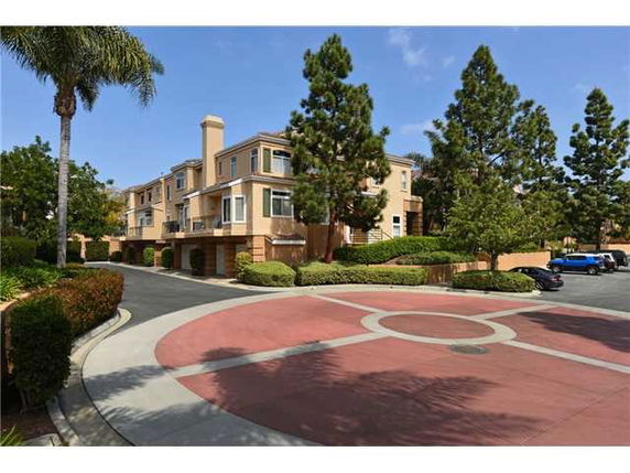 Front view of a multi-story residential building with trees and a driveway.