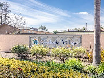 Front view of Creekside Village with a sign and landscaping.